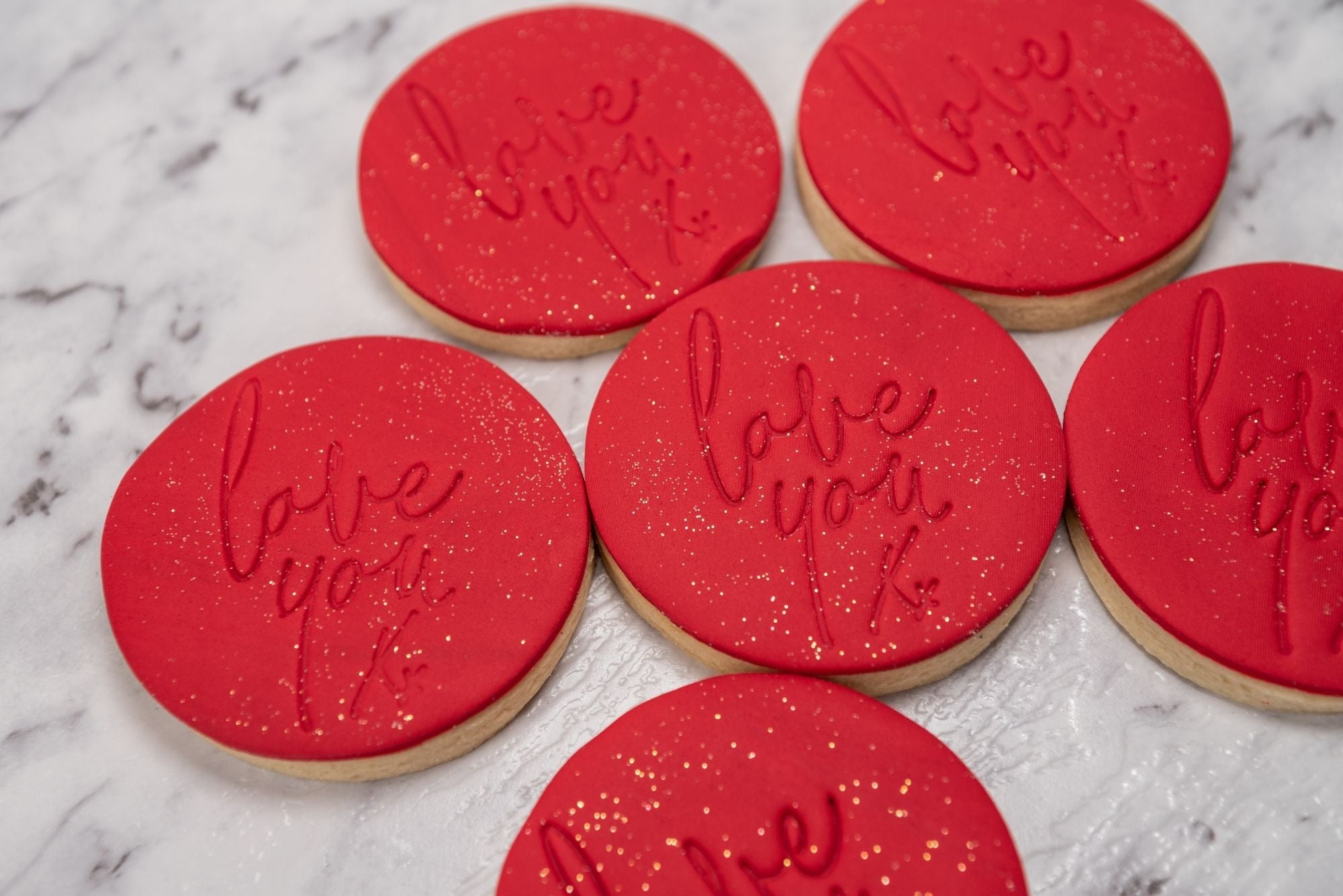 "Love you" embossed red fondant cookies with gold splash